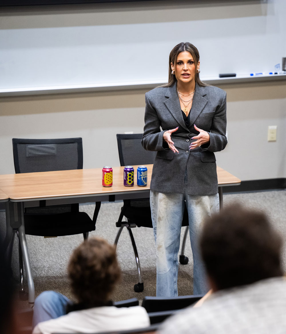 Allison Ellsworth stands next to cans of poppi as she addresses UNT students.