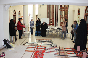 Sheikha Altaf Al-Sabah, at left in red, helped organize the collaboration between UNT faculty member Lesli Robertson, at right with brown scarf, and Al Sadu House in Kuwait. After Robertson's workshop with Al Sadu House, the weavers gathered to view samples of their new designs alongside traditional designs. (Photo courtesy of Patricia Redding)