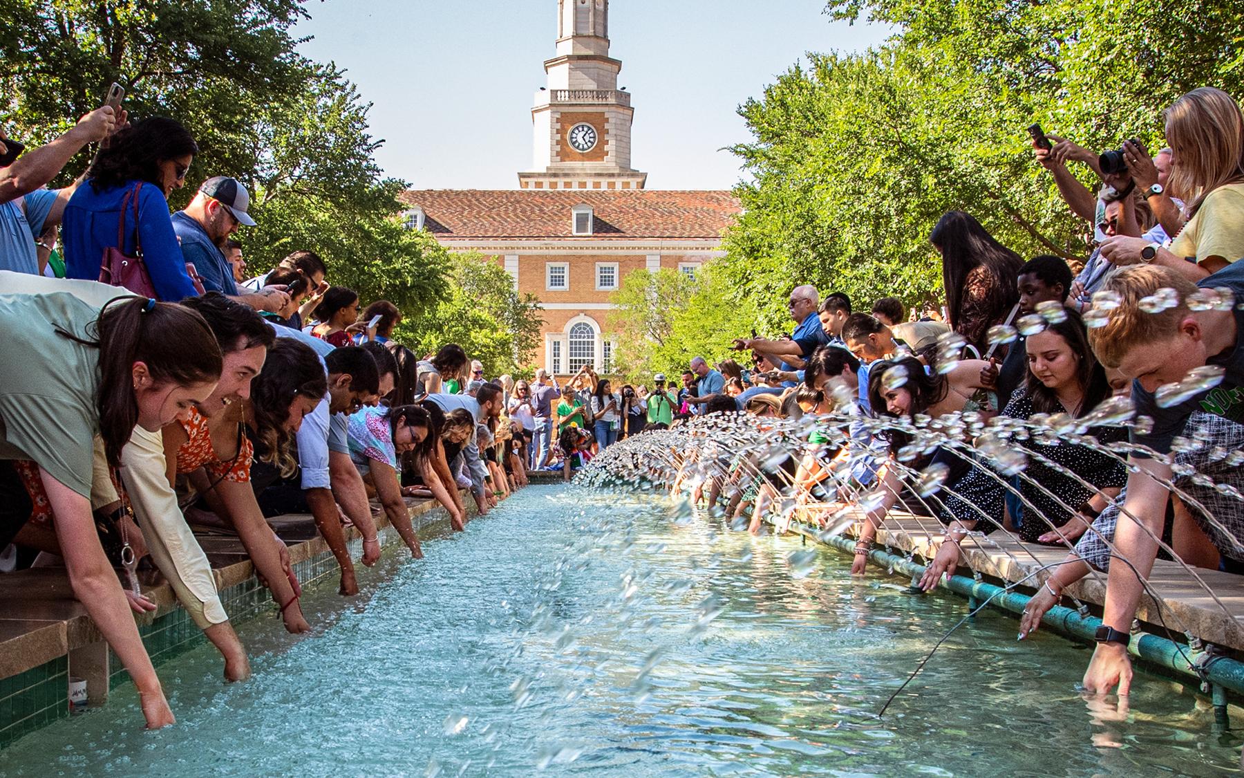 Photo of students dipping class rings in library fountains
