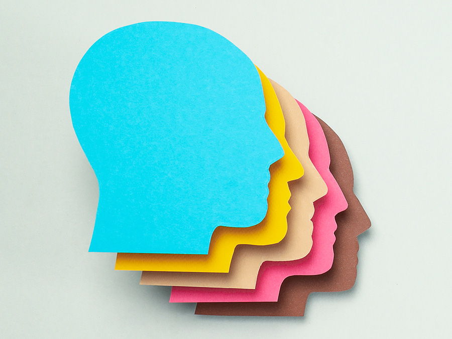 Illustration of human faces in profile made from construction paper in various colors